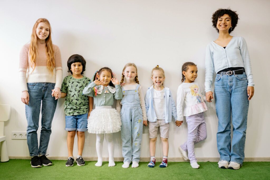Happy group of children and their teachers posing in a classroom setting, showcasing diversity and unity.